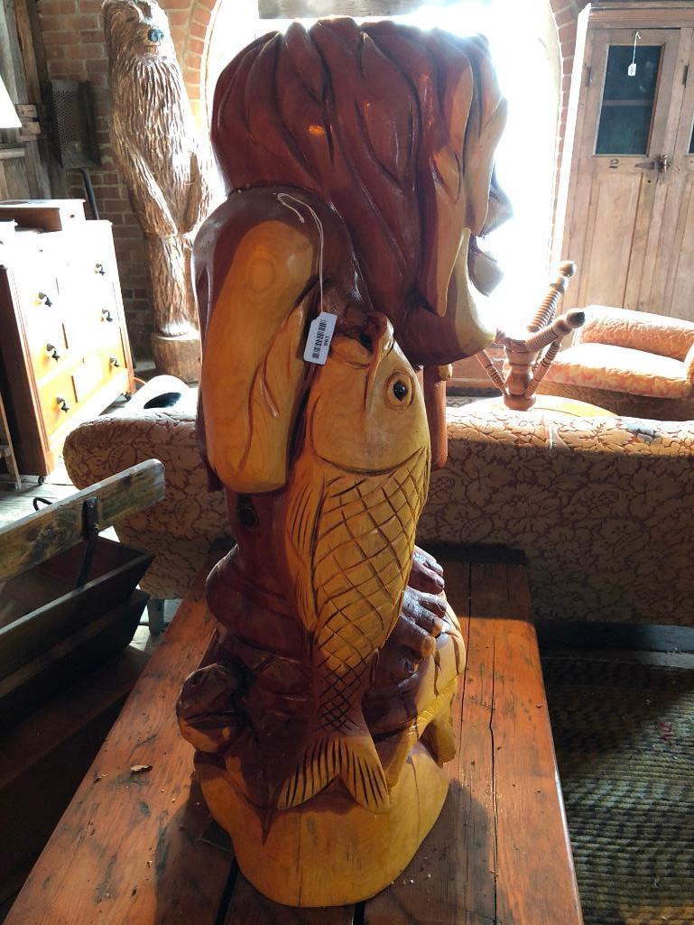 Large, wood carved figure of man with bottle and fish.