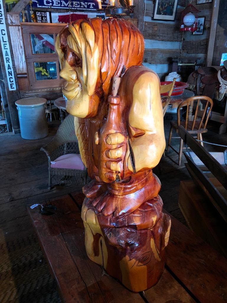 Large, wood carved figure of man with bottle and fish.