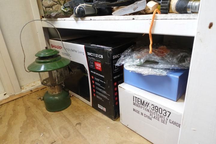 BOTTOM SHELF OF SHED INCLUDING EXTENSION CORDS OLD BOTTLES TOOLS LANTERN AN