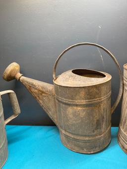 3 galvanized watering cans and a fuel can