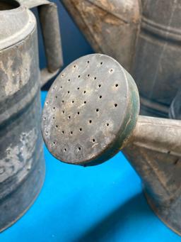 3 galvanized watering cans and a fuel can