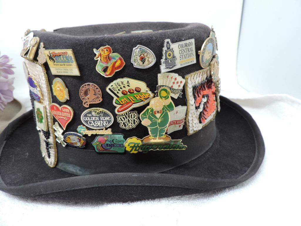 Two festive hats loaded with casino pins.